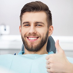man in the dental chair giving a thumbs-up 