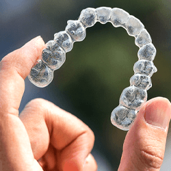 Closeup of patient holding Invisalign in Owings Mills