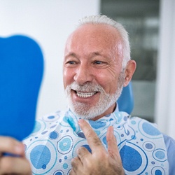 Senior patient checking and pointing to smile in mirror