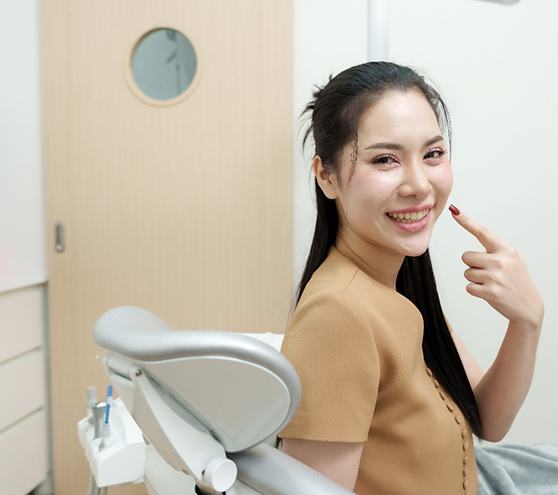 Happy dental patient pointing at her teeth