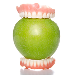 dentures around a green apple