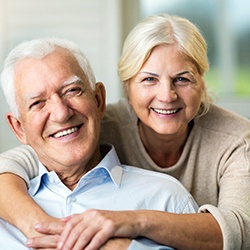 Senior woman and senior man sitting and smiling on couch