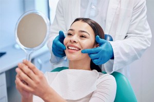 A smiling woman examining her teeth with a dentist
