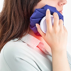 woman using cold compress on cheek  