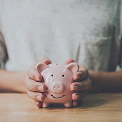 Close-up of man in a grey shirt with a piggy bank