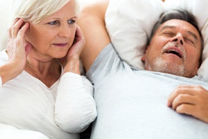 man snoring while wife covers ears awake