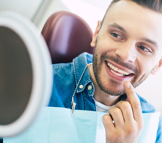 Man smiling at reflection in handheld mirror