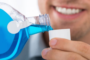 man pouring mouthwash into cup