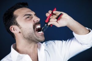 bearded man pulling tooth pliers