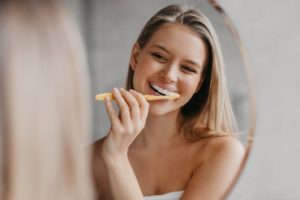 Attractive woman brushing teeth to extend the lifespan of her veneers