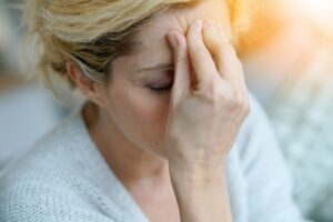 Woman with closed eyes holding forehead suffering from migraine.